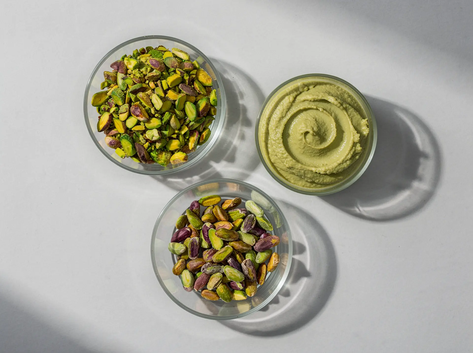 Chopped and whole pistachios and pistachio paste in glass dishes